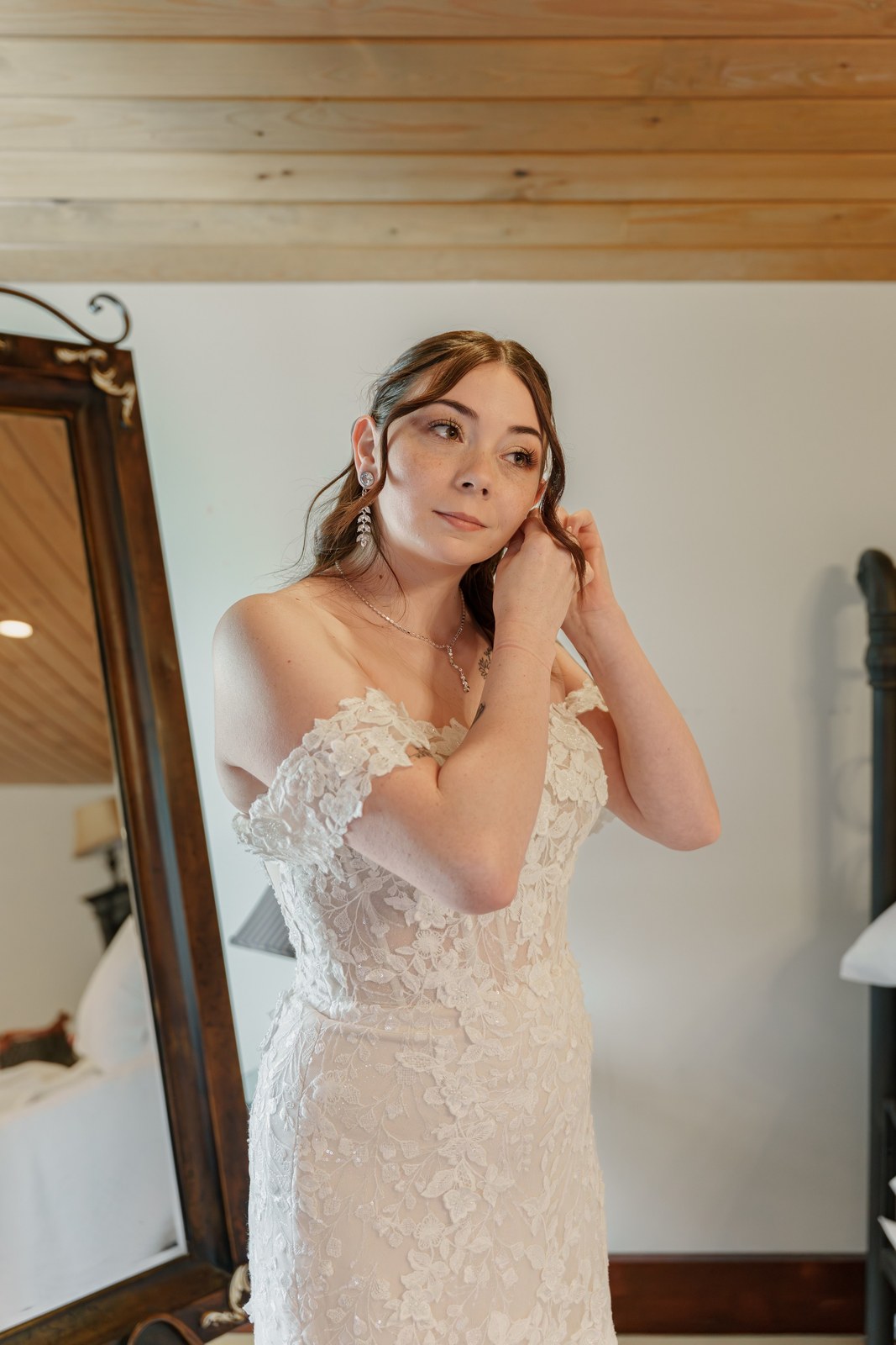 Bride putting on her earrings by a mirror