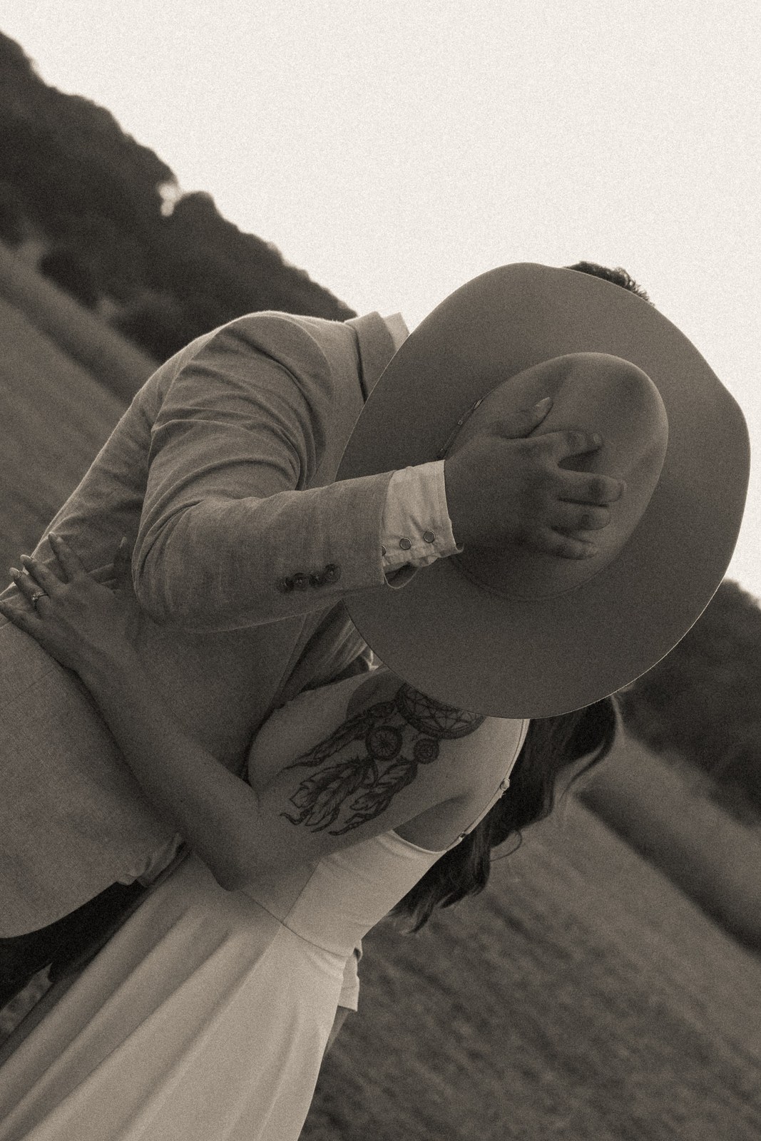 Black-and-white image of a couple behind a cowboy hat