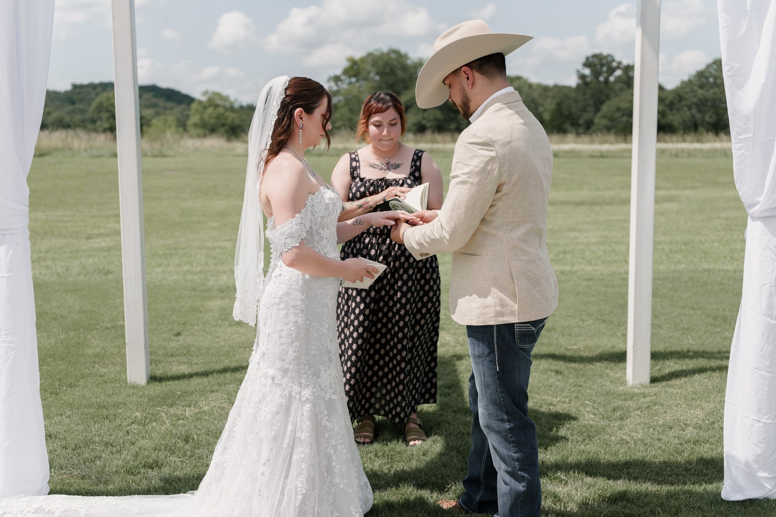 Couple exchanging vows beneath a draped arch