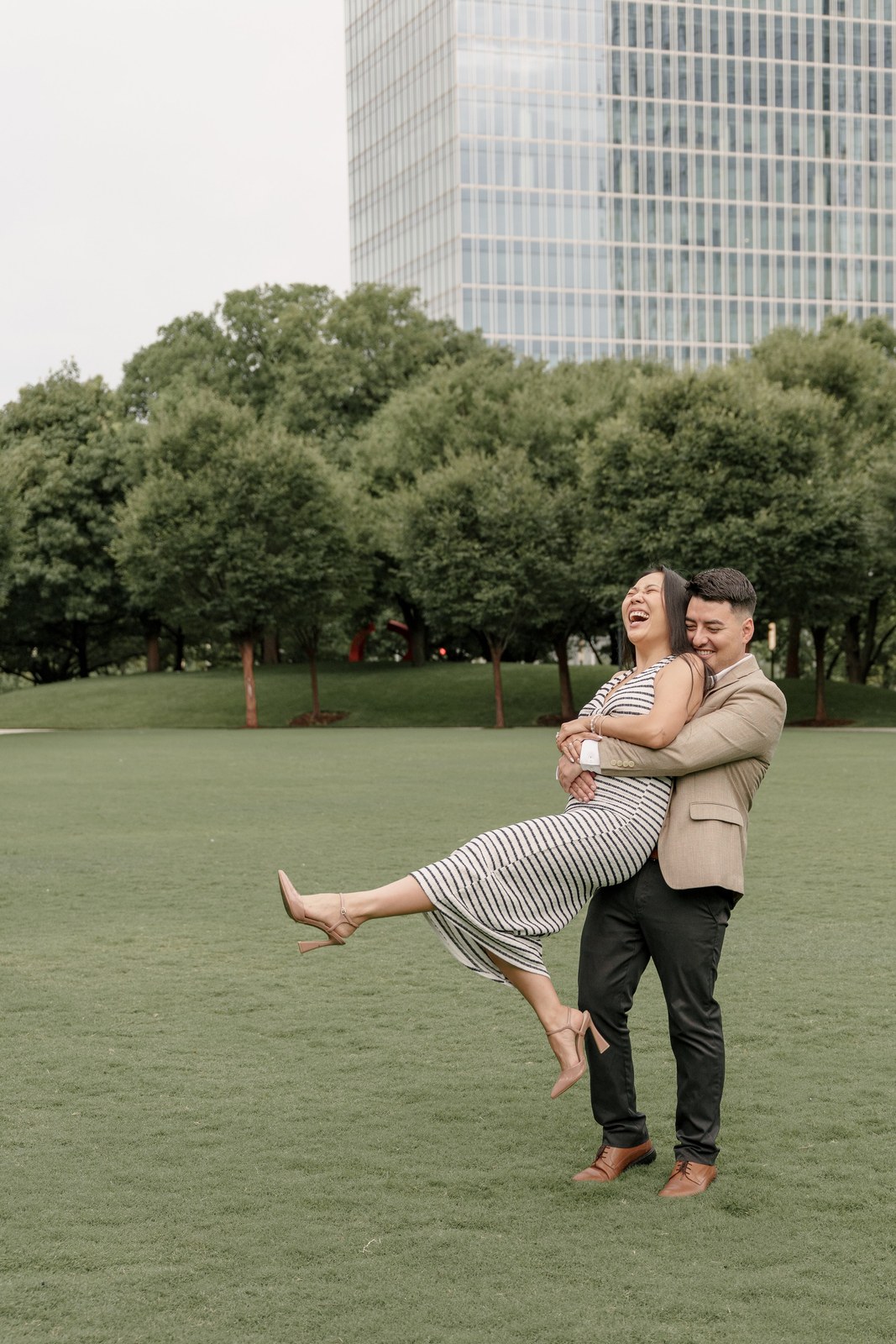 Groom lifting the bride on a park lawn